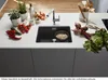 A modern kitchen island with a sink, faucet, and various ingredients like vegetables and herbs. Produktbild-Vorschau