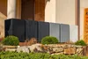 A row of planters in various shades of gray and black are displayed on a stone ledge in front of a building. Produktbild-Vorschau