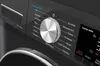 A close-up view of the control panel of a black washing machine, featuring a silver dial and a digital display. Produktbild-Vorschau