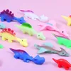 Auswahl an bunten Gummi-Dinosaurierspielzeugen, darunter ein blauer Stegosaurus, ein pinker Pterodaktylus und ein grüner Brontosaurus, auf rosa Hintergrund Produktbild-Vorschau