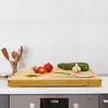 A kitchen counter with a bamboo cutting board, vegetables, and utensils. Anteprima dell’immagine prodotto