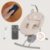A baby swing with accessories, including a remote control and charging cable, displayed on a light background. Produktbild-Vorschau