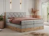 A bedroom scene featuring a king-size boxspring bed with a tufted headboard, dressed with bedding and decorative pillows. The bed has a wooden base and is placed in a room with soft lighting and decorative elements. Produktbild-Vorschau