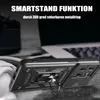 A black phone case with a ring holder is displayed on a textured surface, with a laptop and headphones blurred in the background. Produktbild-Vorschau