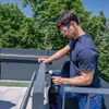 A man is using a Bosch cordless impact wrench to assemble a railing on a balcony or rooftop. Voir les images du produit