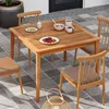 An outdoor dining set with a wooden table and chairs on a tiled patio. Produktbild-Vorschau