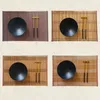 Four different views of woven bamboo placemats with black bowls and gold chopsticks. Produktbild-Vorschau
