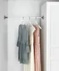 Three dresses hanging on a closet rod next to a white wardrobe. Produktbild-Vorschau