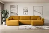 A modern living room with a large, mustard-yellow sectional sofa as the focal point. The sofa is arranged in a U-shape and is placed on a wooden floor with a patterned rug underneath. Two abstract paintings hang on the wall behind the sofa, and a large pot