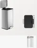 A stainless steel pedal trash can with its lid open and a wall-mounted trash can holder are displayed against a white background. A roll of trash bags is also visible in the lower right corner. Produktbild-Vorschau