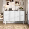 A white sideboard with decorative arches is placed in a well-lit room, with a sofa and a rug visible. Voir les images du produit