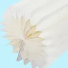 A close-up view of a white, pleated paper decoration, resembling a fan or flower, against a light blue background. Podgląd zdjęcia produktu