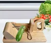 A wooden slicer with a cucumber on it, with vegetables in the background. Náhled obrázku produktu