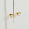 A close-up view of two golden cabinet knobs on a white surface, likely a piece of furniture. Produktbild-Vorschau