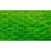 A close-up view of galvanized steel wire mesh with a hexagonal pattern, set against a blurred green background, likely grass. Produktbild-Vorschau