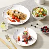 A table setting with plates of food, cutlery, and a glass of water. Produktbild-Vorschau