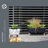 Two planters with plants on a wooden deck in front of blinds. Anteprima dell’immagine prodotto