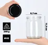 A hand holding a black lid above a clear glass jar, with dimensions and weight information displayed. Anteprima dell’immagine prodotto