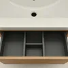A close-up view of an open bathroom vanity drawer with a sink above it. Voir les images du produit