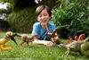 A young boy is playing with dinosaur toys on the grass in a backyard. Produktbild-Vorschau