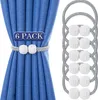 A set of 6 magnetic curtain tie-backs with decorative white beaded spheres and a braided gray band, shown holding back blue curtains. A separate group of the tie-backs is displayed on the right side of the image. Produktbild-Vorschau