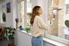 A woman is cleaning a window with an electric window cleaner. Voir les images du produit
