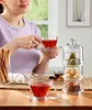 A woman is enjoying tea and pastries at a table. Anteprima dell’immagine prodotto