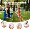 A woman is kneeling next to a dog in a metal pet playpen outdoors. Produktbild-Vorschau