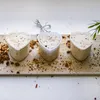 Three heart-shaped cheese molds filled with a white mixture and sprinkled with spices on a wooden board. Produktbild-Vorschau