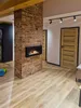 A modern living room with a brick fireplace and wooden doors. Anteprima dell’immagine prodotto