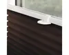 A close-up view of a brown pleated blind attached to a white window frame. Produktbild-Vorschau