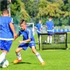 Children playing soccer on a field with a mini goal. Produktbild-Vorschau