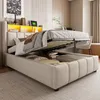 A bed with its storage compartment open, revealing stored items. The bed is in a room setting with a poster on the wall and a desk in the background. Náhled obrázku produktu