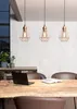 A dining table with a laptop and a book, under three pendant lights. Voir les images du produit