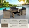 A rattan lounge set with dark gray cushions and a black glass coffee table is set up on a patio next to a swimming pool with palm trees and the ocean in the background. Náhled obrázku produktu