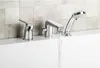 A chrome bathtub faucet with a handheld showerhead is shown on the edge of a white bathtub, with a tiled wall in the background. Water is flowing from the faucet. Podgląd zdjęcia produktu