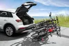 A white car with its trunk open, loaded with bicycles on a rack, parked near a beach. Produktbild-Vorschau
