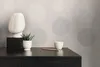 A decorative bust and a potted plant on a dark wooden dresser, with a patterned wallpaper in the background. Produktbild-Vorschau