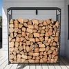 A metal firewood rack filled with logs, placed outdoors against a white house. Podgląd zdjęcia produktu