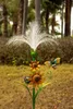 A decorative solar garden stake with a dandelion-like top, two sunflowers, and a bee, placed outdoors in a garden setting. Produktbild-Vorschau