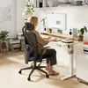 A woman is working at a standing desk in a modern home office setting. Anteprima dell’immagine prodotto