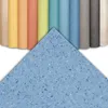 A collection of rolled-up flooring samples in various colors, with a large sample of blue speckled flooring in the foreground. Podgląd zdjęcia produktu