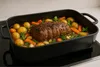 A roast with potatoes and carrots in a black roasting pan. Produktbild-Vorschau
