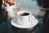 A white cup of coffee on a saucer on a reflective surface. Podgląd zdjęcia produktu