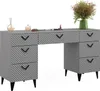A gray vanity table with a geometric pattern on the drawers, set against a white background. Decorative items like a diffuser, perfume bottles, sunglasses, and a vase with flowers are placed on top. Podgląd zdjęcia produktu