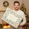 A man is holding a large advent calendar in a festive, decorated room with a Christmas tree in the background. Produktbild-Vorschau