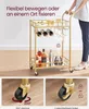 A person is pushing a gold bar cart with bottles and glasses on it. The image is split into three sections, with the main image showing the cart and a person, and two smaller images showing close-ups of the wheels. Produktbild-Vorschau
