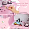 A close-up view of a pink wooden toy kitchen, highlighting features like a turning knob, a sink with running water and toy food, and a pot on a stovetop. Produktbild-Vorschau