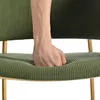 A hand is pressing into the seat of a green corduroy chair with gold legs. Voir les images du produit