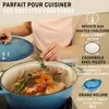 A person is adding rosemary to a chicken in a blue Dutch oven. Produktbild-Vorschau